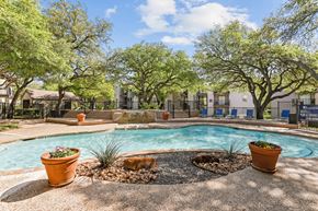 Dallas apartment for rent - A pool surrounded by trees and potted plants at The Park on Preston in Dallas, TX
