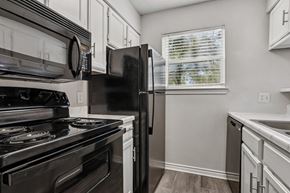Dallas apartment for rent - A kitchen with a black refrigerator, stove, and microwave at The Park on Preston in Dallas, TX