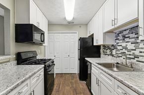 Smyrna apartment for rent - Apartment kitchen with white cabinets and black appliances at Oakley Run apartments in Smyrna, GA