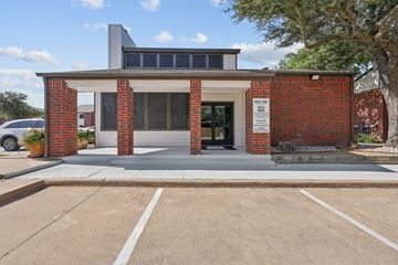 Wylie apartment for rent - A red brick building with a white entrance and a sign on the right side.