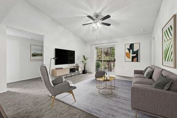 Gainesville apartment for rent - A living room with a grey sofa, a grey chair, a grey rug and a white ceiling fan.