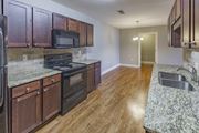 Titusville apartment for rent - a kitchen with wood cabinets and granite counter tops and black appliances
