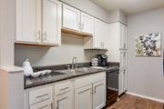 Shreveport apartment for rent - A kitchen with white cabinets and a grey countertop in the model apartment at Stone Canyon apartments in Shreveport, LA.