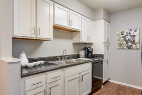 Shreveport apartment for rent - A kitchen with white cabinets and a grey countertop in the model apartment at Stone Canyon apartments in Shreveport, LA.