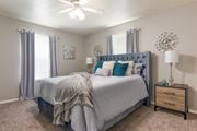 Shreveport apartment for rent - A bedroom with a large bed and a ceiling fan in the model apartment at Stone Canyon apartments in Shreveport, LA.
