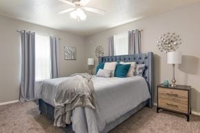 Shreveport apartment for rent - A bedroom with a large bed and a ceiling fan in the model apartment at Stone Canyon apartments in Shreveport, LA.