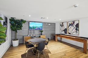 West Miami apartment for rent - Resident gaming zone with a TV and a potted plant and shuffleboard at Twenty2 West luxury apartments in Miami, FL