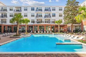 Houston apartment for rent - A large swimming pool in front of a multi-story apartment building at The Grand At Upper Kirby in Houston, TX