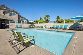 Olympia apartment for rent - A pool with blue lounge chairs and green chairs at The Madison apartments in Olympia, WA