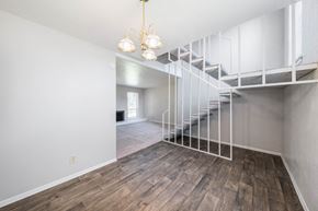 Euless apartment for rent - A room with a wooden floor and a staircase with a metal railing.