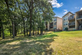 Euless apartment for rent - A grassy area with trees and apartment buildings in the background.