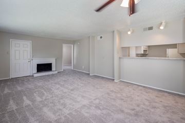 Euless apartment for rent - A living room with a fireplace and a ceiling fan.