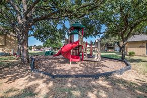 Euless apartment for rent - A playground with a red slide and a green roof.