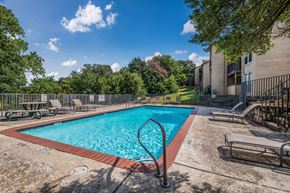 Euless apartment for rent - A swimming pool surrounded by trees and a building.