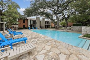Austin apartment for rent - A pool surrounded by blue and white lounge chairs at Westdale Pointe in Austin, TX