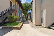 Dallas apartment for rent - A yellow apartment building exterior and paved walkway at Windridge on the Parkway in Dallas, TX