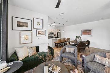 Euless apartment for rent - A living room with a green couch, a grey couch, a coffee table, and a dining table with chairs.