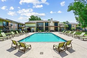 Houston apartment for rent - a swimming pool with chaise lounge chairs and a building in the background