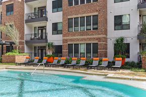 Houston apartment for rent - A pool area with chairs and apartments in the background at Muse at Museum District apartments in Houston, TX
