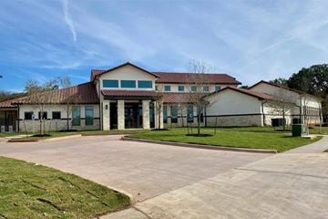 Austin apartment for rent - A large building with a red roof and a parking lot in front.