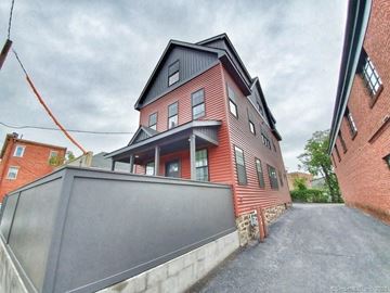 Norwalk apartment for rent - A red brick house with a black roof and a grey garage door.