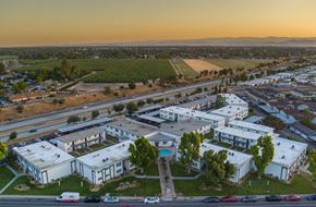 Clovis apartment for rent - A large white building with a pool in the middle of a grassy area.
