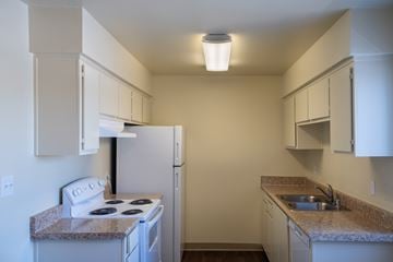 Clovis apartment for rent - A small kitchen with a white stove and a refrigerator.