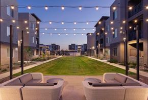 Glendale apartment for rent - A row of white chairs are set up on a patio with a lawn and apartment buildings in the background.