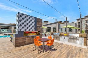 Glendale apartment for rent - A wooden table with four orange chairs is in the foreground of an outdoor kitchen area.
