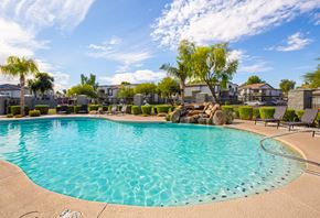 Phoenix apartment for rent - a resort style pool with a waterfall and trees in front of apartment buildings