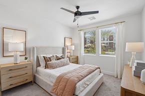 Mesa apartment for rent - A bedroom with a large bed, a ceiling fan, and a dresser with a mirror.