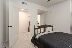 Tucson apartment for rent - A bedroom with a black bed and a wooden stick leaning against the wall.