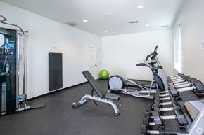 Tucson apartment for rent - A gym with a variety of equipment including a leg press machine, a rowing machine, and a bench with a green ball on it.