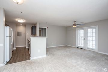 Perry apartment for rent - A spacious living room with a ceiling fan and a kitchen area with a refrigerator and a microwave.
