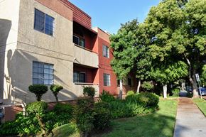Glendale apartment for rent - A building with a red and beige exterior is surrounded by greenery.