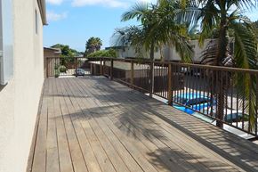 Santa Barbara apartment for rent - A wooden deck with a pool and palm trees in the background.