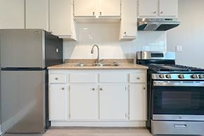 Hollywood apartment for rent - A kitchen with a black refrigerator and white cabinets.