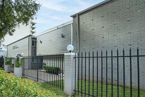 Houston apartment for rent - A black metal fence in front of a grey building.