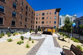 Reno apartment for rent - A courtyard with a fire pit and benches is surrounded by brick buildings.