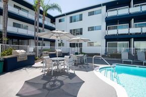 Torrance apartment for rent - A pool area with a table and chairs and a palm tree.