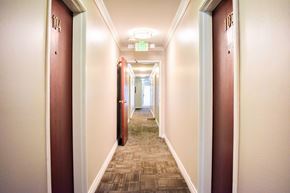 Los Angeles apartment for rent - A long hallway with doors on both sides and a green exit sign above.