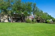 Tyler apartment for rent - View from the loop of the property with lush grass, flags flying high, and exterior of building in the background