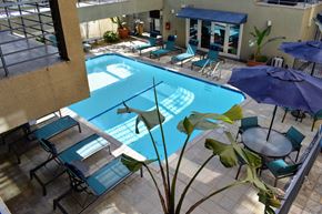 Los Angeles apartment for rent - Elevated view into community pool with seating, lounge chairs, and tropical plants