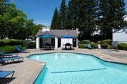Folsom apartment for rent - A pool with a blue umbrella and chairs.