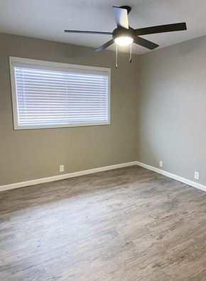 Manteca apartment for rent - living area with wood look flooring, well lit window, and ceiling fan