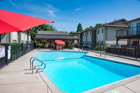 Sacramento apartment for rent - View of gated community pool with seating under umbrellas and covered area with picnic table and seating