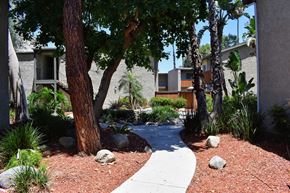 Canoga Park apartment for rent - View of exterior buildings and side walk winding in between with lush landscaping and trees