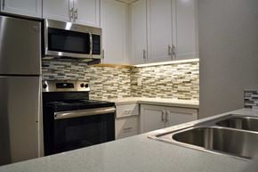 Canoga Park apartment for rent - Kitchen with stainless appliances, tiled backsplash, and white cabinets