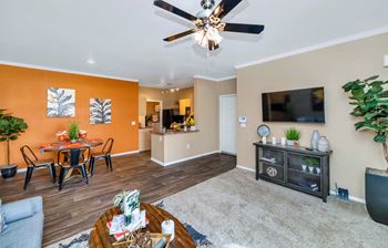 The living room and dining area of a home with a ceiling fan and a tv
