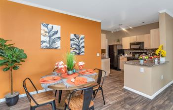 A dining area with a table and chairs and a kitchen in the background